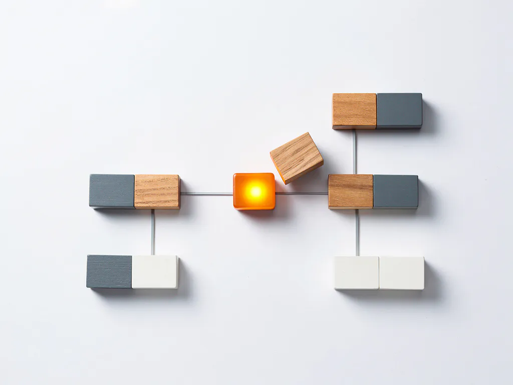 Miniatuur organogram van houten blokken in transformatie, met een gloeiend amberkleurig blok als draaipunt op wit oppervlak.