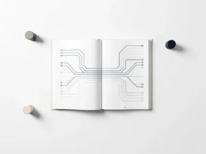Open boek met uitwaaierend pagina's als leerkaart, omringd door drie speeltokens in salie, ivoor en marineblauw op wit oppervlak.