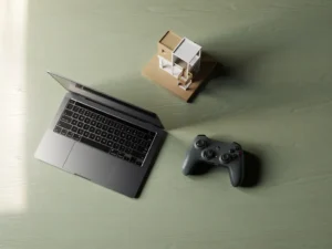 Houten bureau met laptop, gamecontroller en architectuurmaquette in driehoeksopstelling, zacht natuurlijk licht.