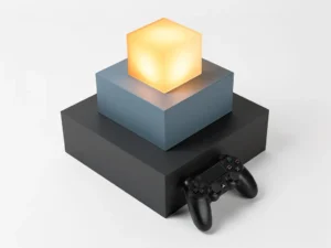 Gestapelde geometrische blokken in amber, leisteenblauw en antraciet met een gamecontroller ertegenaan, gefotografeerd vanuit driekwartperspectief.