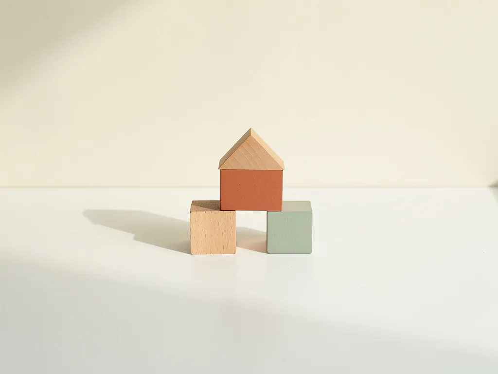 Houten speelblokken in terracotta en saliegroen op een wit bureau, met één uitvergroot blok als middelpunt.